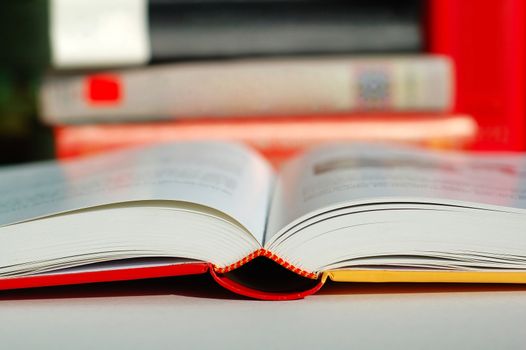 An opened book with pile of books beside it
