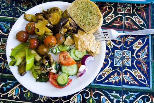 Plate with vegetarian food on the figured table