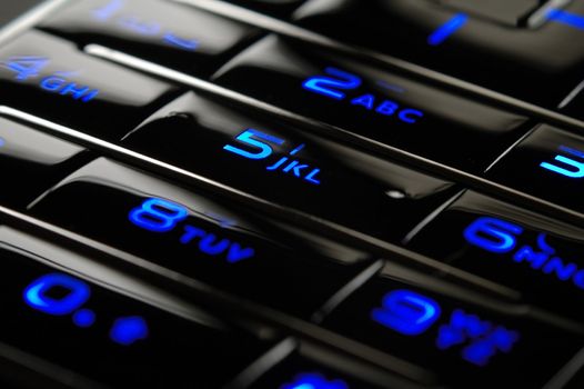 Close up shot of blue mobile keypad under dark environment