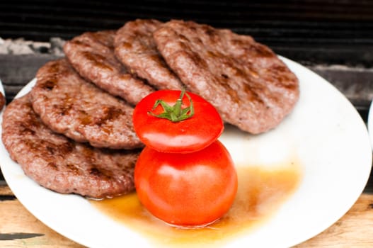 cooked on grill meat is on the plate with tomato