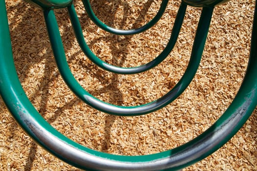Green circular playground ladder with an abstract view looking down at wood chips
