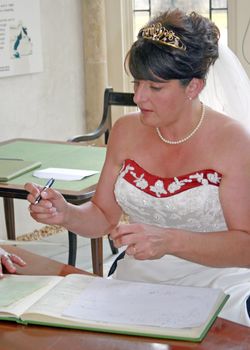 A Bride signing the register after her wedding.