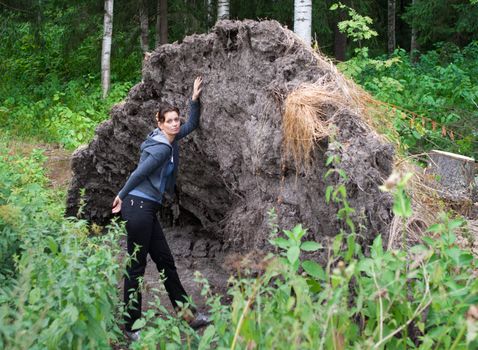 Young woman leaning on the broken tree in forest.