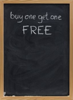 buy one get one free offer - discount sale advertisement handwritten with white chalk on blackboard, copy space below