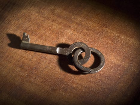 An old key on a keyring over a wooden table.