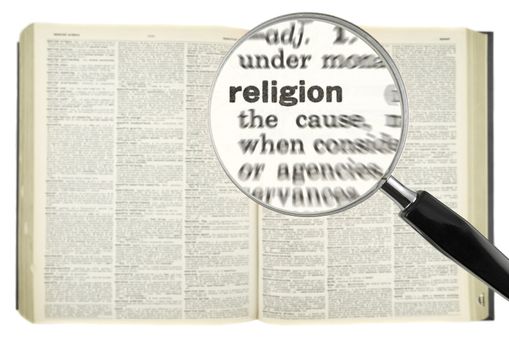 A magnifying glass on the word RELIGION on a dictionary.