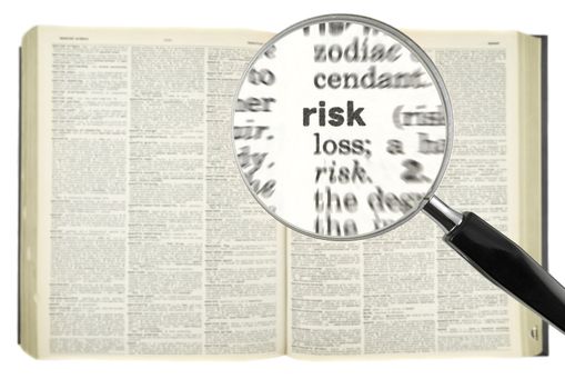 A magnifying glass on the word RISK on a dictionary.