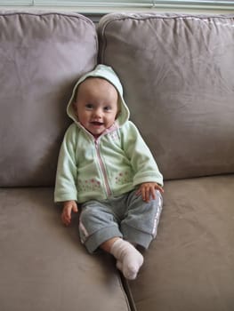 Little caucasian baby girl sitting on a sofa.