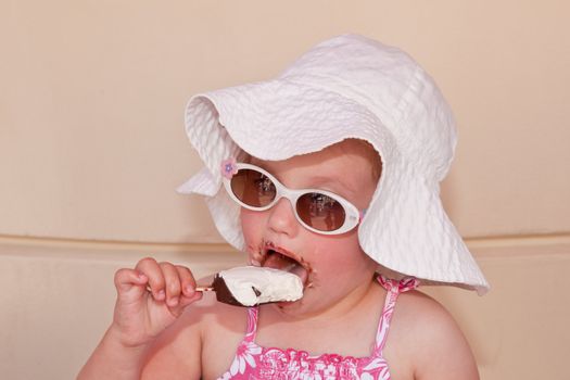 Cute little European toddler girl enjoying a piece of ice cream.