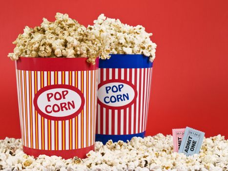 Two popcorn buckets over a red background.