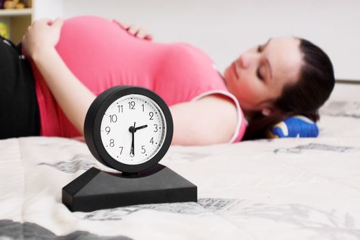 pregnant lying woman and clock, focus on clock