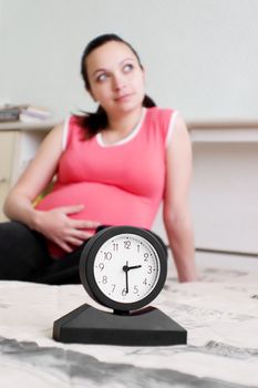 Pregnant woman and clock, focus on clock