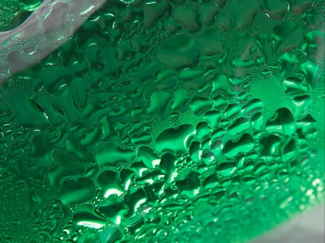 Many small water droplets on a transparent green surface
