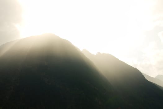 Bright beams of sunlight breaking through a mountain range