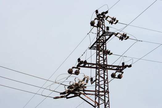 Old rusty electric pillar against gray sky