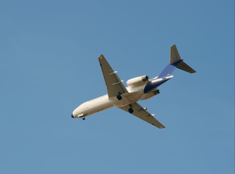 White commercial airplane landing against clear blue sky