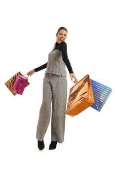 Full body view of young attractive woman in business wear,  going shopping with lots of colorful shopping bags. Isolated on white background.