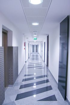 Long hallway in corporate building with doors at the end.