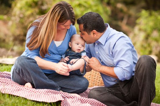 Happy Mixed Race Family Having a Picnic and Playing In The Park.