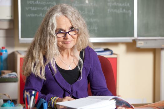 Teacher sitting behind her desk checking on the kids homework