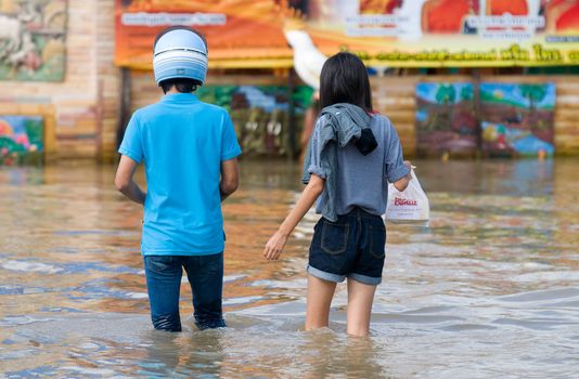 NAKHON RATCHASIMA - OCTOBER 24: Young couple wading through the streets of the city during the worst monsoon flood in 50 years on October 24, 2010 in Nakhon Ratchasima, Thailand.