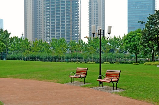 The walk way and bench of city park with building as background