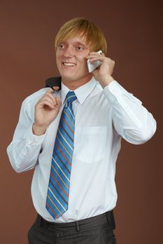 A young man talking on the phone on a brown background