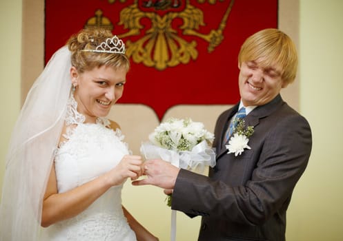 Laughing bride and groom wear a ring