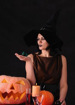 Young witch with a pumpkin on a black  background