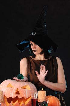 Young witch with a pumpkin on a black  background