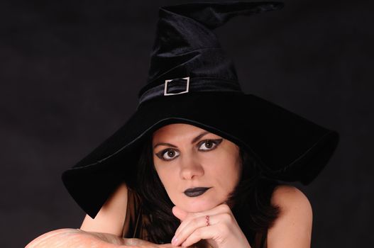 Young witch with a pumpkin on a black  background