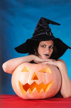 Young witch with a pumpkin on a blue  background