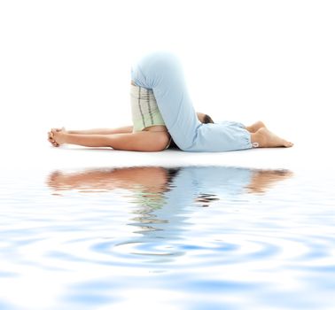 sporty girl practicing halasana plow pose on white sand