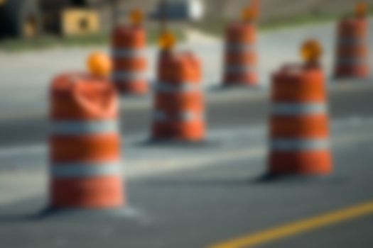 Construction Barrel Lights Blur shows orange reflector barrels insead of highway cones. A road is under repair or rennovation under an improvement plan.
