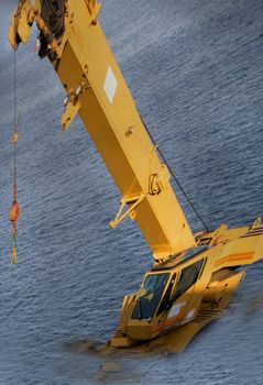 Construction Crane Needs Help is an abstract conceptual piece of equipment that partially submerged in the waters of Puget Sound near Seattle Washington. It appears that there has been a flood or flooding from the ocean a major disaster.
