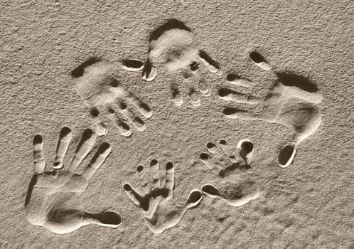 A family of handprints pressed into the sand