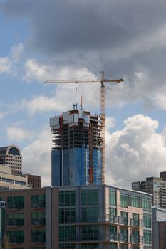 Downtown Seattle Construction v1 is a piece of new construction to the downtown Seattle Skyline. There is a large yellow construction crane set at the top of the building. There is a stormy sky overhead with dark clouds.
