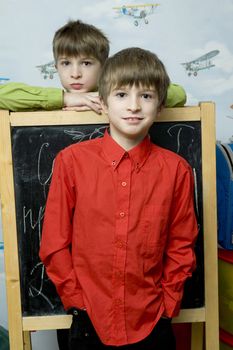 Happy twins brothers standing at wall. Wallpaper with airplane