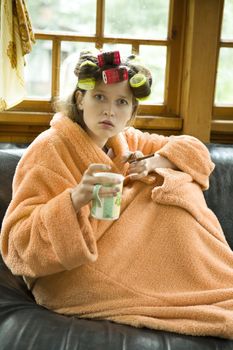 Beautiful girl in hair curlers with a cup of tea.