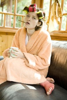 Beautiful girl in hair curlers with a cup of tea.