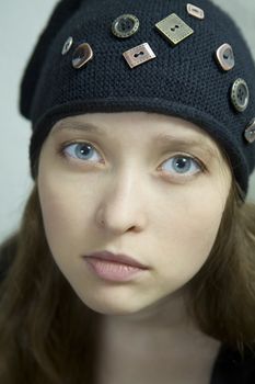 closeup portrait young attractive  girl with long hair and blue eyes. She wearing hat
