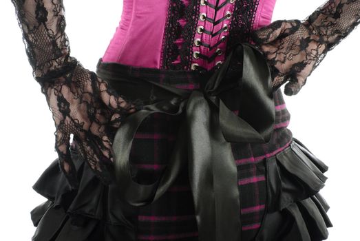 Back of the woman in pink corset with laces and original skirt. Her hands in gloves fasten big black bow. Isolated on white background