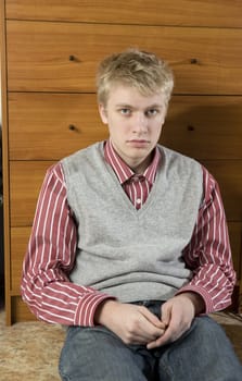 portrait of young handsome blond man sitting on the floor