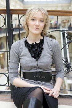 young attractive woman sitting at railing in state department store. Shopping. Moscow