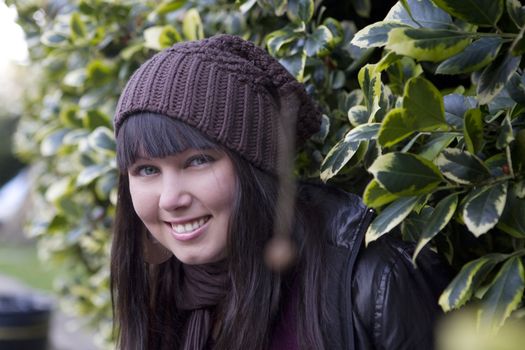 smiling girl looking from  green bush