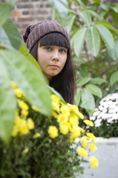 smiling girl looking from  green bush