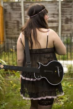 Attractive young woman playing guitar standing at 