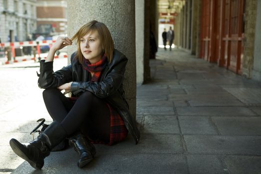 young attractive girl with red hair sitting on street, waiting