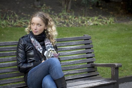 adorable girl sitting on the bench in the park