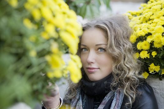 portrait of young attractive blond girl with curl hair sitting on the stoneblock pavement  in the park